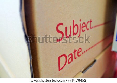 close up image to side of paper box for stock report file with red text "subject  and date".concept equipment in office