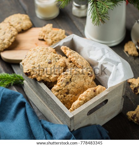 The perfect tasty breakfast.Oatmeal cookies with chocolate in wooden box and green tea with lemon in mugs on a dark background with a Xmas tree. Best useful Cookies. 
