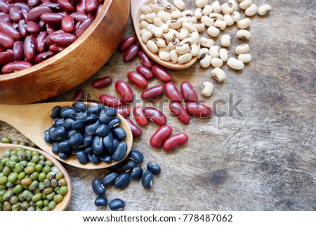 Healthy food with whole grains is red beans,soy beans,black turtle bean,mung bean in wooden spoons and wooden cups on the old wooden table. above view cereal and copy space for add messages.