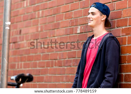 Teenage boy with skateboard standing next to the wall