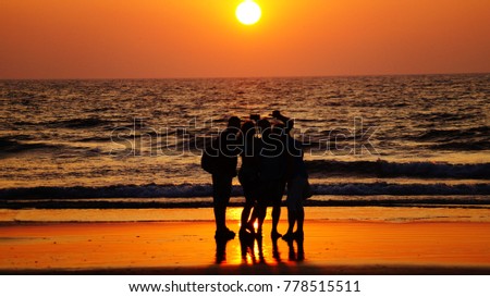 Group of friends photographed against the background of the sea and sunset. Friends doing selfie in front of the beach. Take a picture during sunset. Silhouette of the friends.