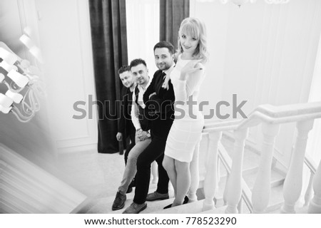 Three stylish bearded man well dressed with one blonde girl in white dress posed. Musician band or singers.