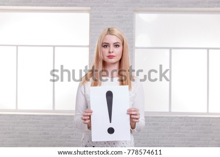 A girl holding in hands a sheet of paper with a exclamation mark.