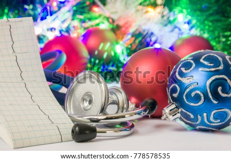 Medical cardiology Christmas and New Year photo - stethoscope and electrocardiogram tape are located near balls for Christmas tree in blurry background with electric garlands lights and toys