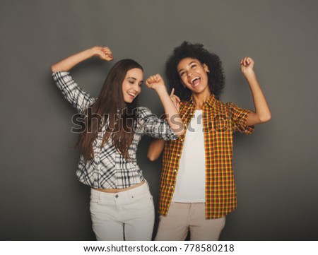 Multiethnic friendship and support concept. Black and caucasian girls in posing and having fun at gray studio background with copy space