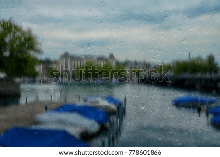 Glass wet city landscape background. Rain in Zurich, Switzerland. Rain drops on the windowpane, a surface with reflection, a blurred rainy landscape. Blurred texture background.