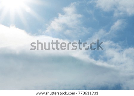 Sun shining on the blue sky with clouds, looking up view