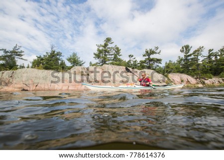 A young man kayaks in a sea kayak on Georgian Bay in Ontario, Canada. 