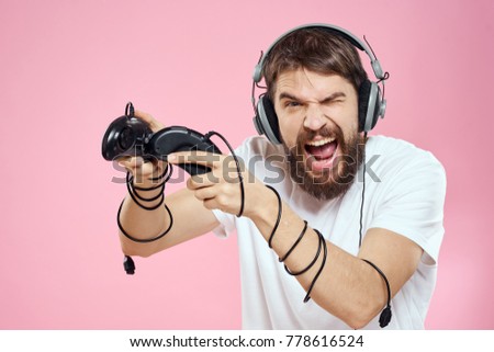  man in earphone plays through joystick on pink background                              
