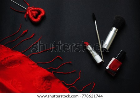 
Red lipstick, lacquer, silk handkerchief on a black background. Valentine's Day
