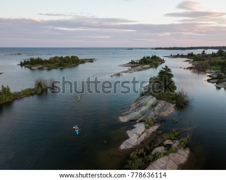 An aerial view group of seniors in sea kayaks camping and paddling on the Great Lakes in northern Canada.