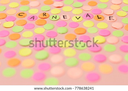 Hand written the word in Italian language Carnevale in each colorful confetti. Warm colors: pink, yellow and orange. Carnival party background concept, space for text.