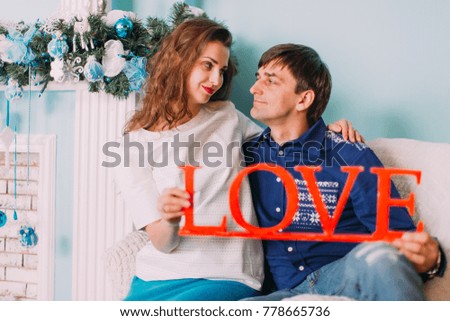 New Year's picture of happy family on background of Christmas decorations. Beautiful young couple hugging and smiling