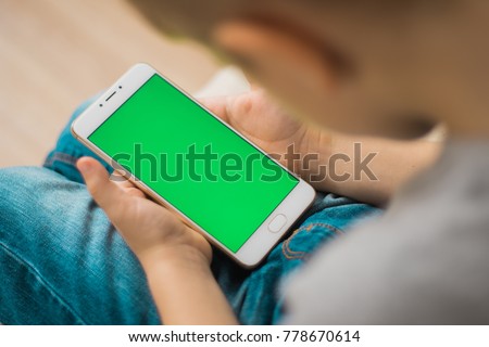 The child is holding a phone in his hand with a green screen for Royalty-Free Stock Photo #778670614