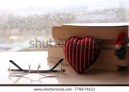 A lovely gift for Valentine's day. Reading a lovely books in front of the window in a rainy day. Coffee and book on the woody table. Glasses and christmas concept.