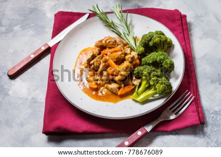 Beef goulash with vegetables and broccoli on rustic concrete background.