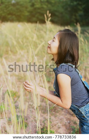 Young Asian girl playing in the grass field in the beautiful sunny day.