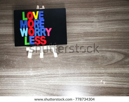 "love more worry less" quote with description on the wooden table as a background.