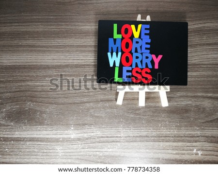 "love more worry less" quote with description on the wooden table as a background.