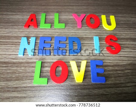 "all you need is love" quote with description on the wooden table as a background.