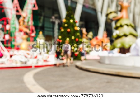 Blurred picture of Christmas tree and various colored balls. The top of it is star. It was set in the open. There is a sky and clouds background image.