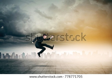 Picture of young male manager looks hurry while running with skyscrapers in the background