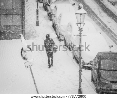 A black and white picture of a person walking into the city in the middle of a snow blizzard in the German City of Braunschweig.