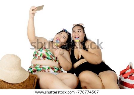 Two obese women taking selfie a picture while eating ice cream. Concept of summer vacation