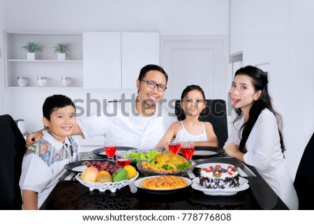 Image of beautiful family looking at the camera while having a dinner together in the kitchen
