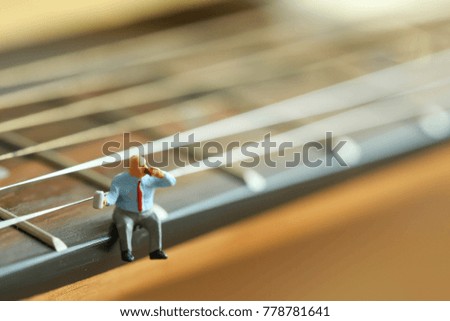 Miniature people : Businessman sitting on acoustic guitar. time of relax or music relax concept.