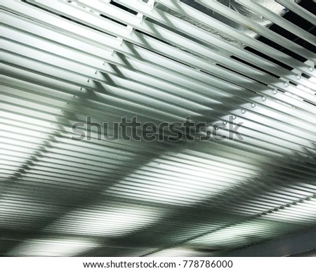 A ceiling is made from aluminum silver bars. A background iron texture is an industry style.