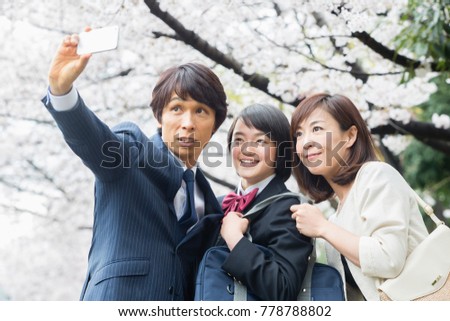 A family taking pictures under the cherry blossoms