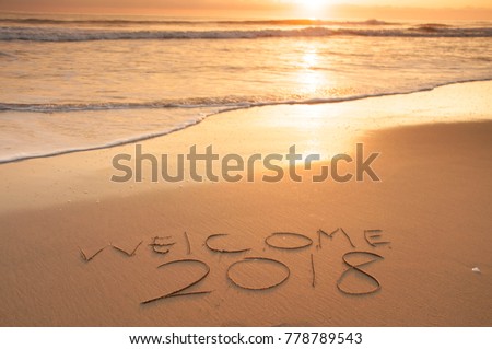 2018  and happy new year greeting written on the beach sand