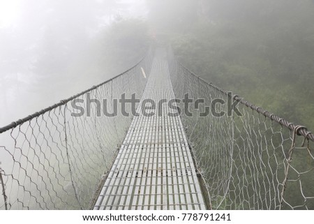 Suspension bridge covered by mist, Himalaya Nepal
