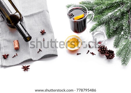 Warm mulled wine with citrus and spices for winter evening near spruce branch on white background copyspace