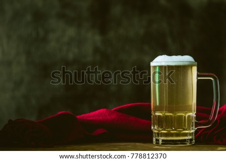 Mug of beer with red scarf on the wooden table. Free space for text