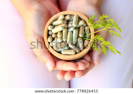 Girl hands holding herbal capsules in wooden bowl Royalty-Free Stock Photo #778826455