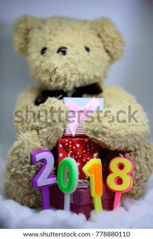 Teddy bear with gift boxes and number 2018 of candles in soft background,decoration for New Year 2018 celebration