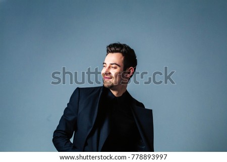 Portrait of a young handsome man in a suit, looking to the side, against plain studio background