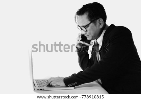 Businesspeople in Asia are using their mobile phones by typing on a portable computer. Financial stress. Black and white photo on white background