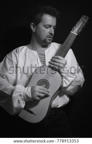 Man playing spanish renaissance instrument vihuela de mano over black 

