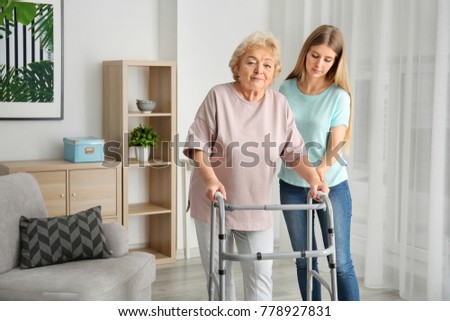 Young woman and her elderly grandmother with walking frame at home Royalty-Free Stock Photo #778927831
