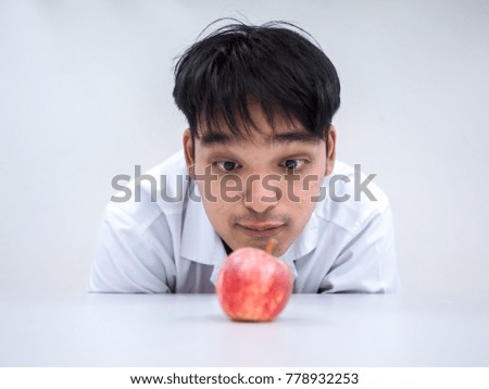 Picture of young scientist looking a blur red apple on white table