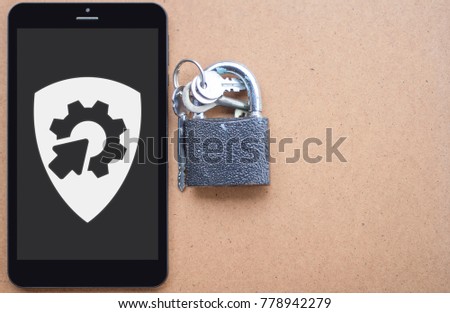 Integration Safety and Security API System Mobile Computing Template concept. Tablet computer with shield gear arrow icon on a display and lock keys on a wooden background.