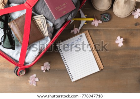 Plan trip on notebook and prepare accessories and travel items for winter trip on old wooden board, flat lay, top view background