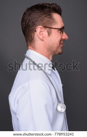 Studio shot of handsome man doctor against gray background