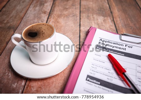 On the desk there is an Application form for hiring and a cup of coffee. The picture can be used for jobs hiring.