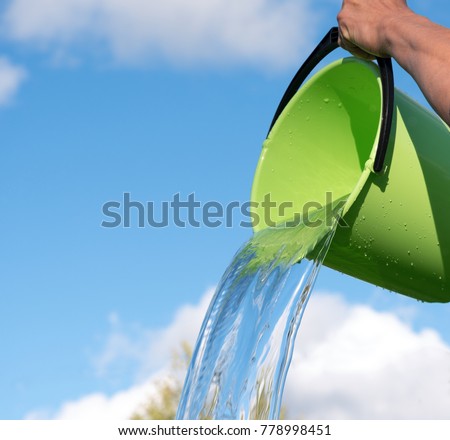 Pouring water and bucket against blue sky. Royalty-Free Stock Photo #778998451