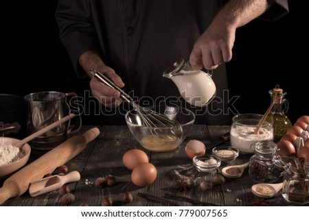 The confectioner's hands pour milk into bowl of eggs, isolated on black background