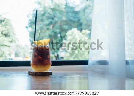 close up ice americano with lemon in coffee shop background.